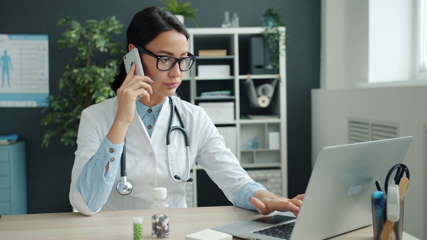Profissional da saúde utilizando notebook em ambiente de consultório